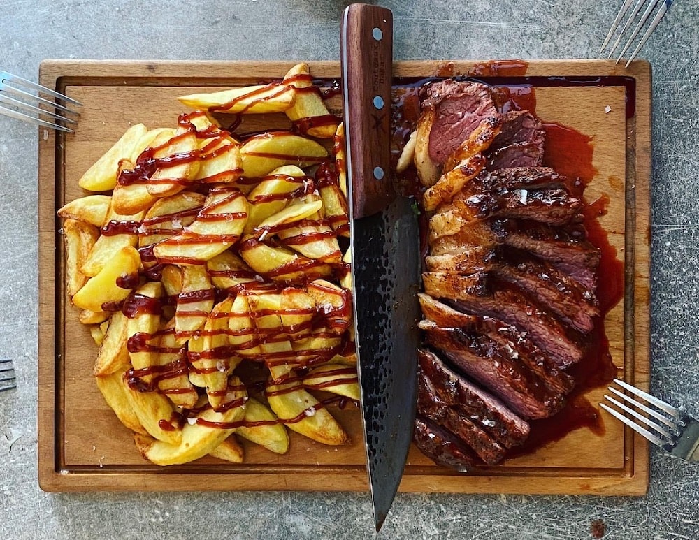 steak and potato wedges on a wooden cutting board